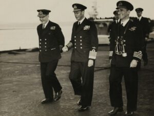 grayscale photo of three men walking on concrete pavement