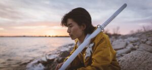 woman in yellow jacket standing on rocky shore during daytime