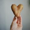 A person holding a heart shaped cookie in their hand